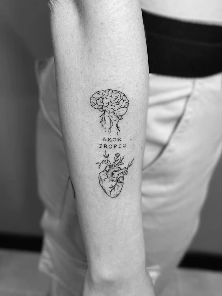 Tatuaje de línea fina de cerebro y corazón con frase en el brazo