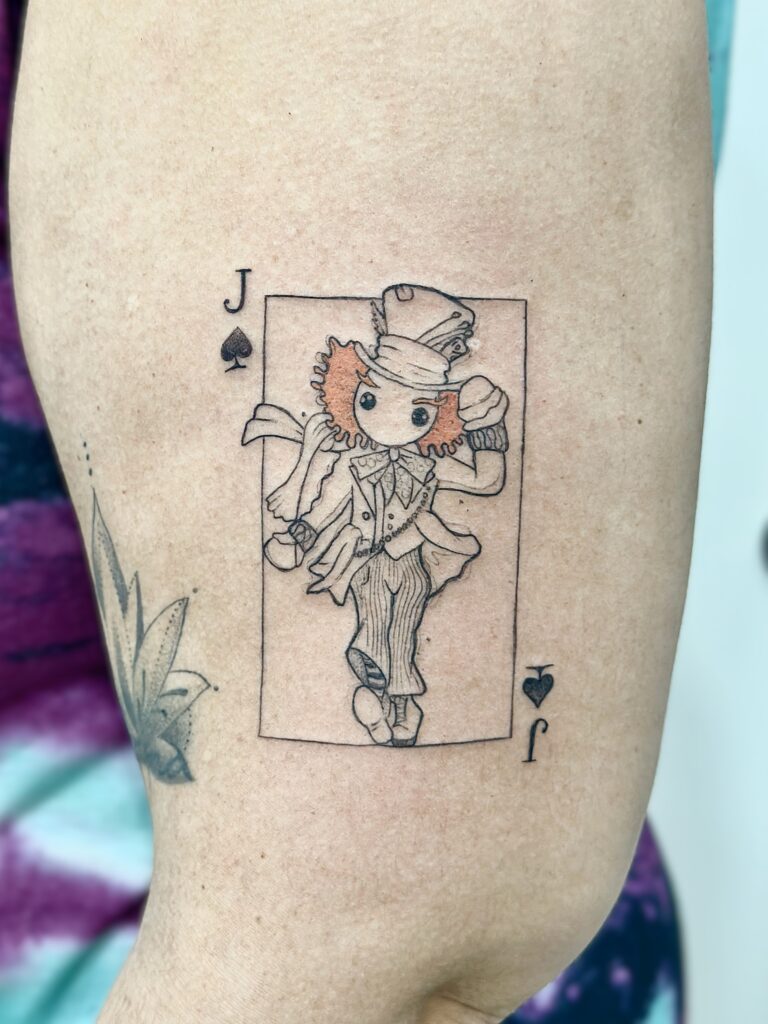 Tatuaje de carta de baraja (joker) con detalle en color en el brazo