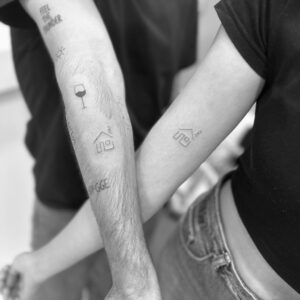 Tatuaje micro de casitas en pareja en brazo