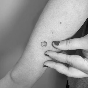 Micro tatuaje de concha en brazo