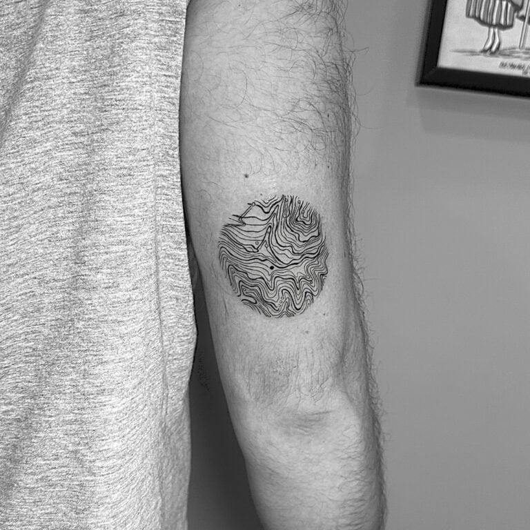 Tatuaje de línea fina de líneas abstractas en un círculo en el codo