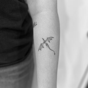 Tatuaje línea fina de dragón en el brazo