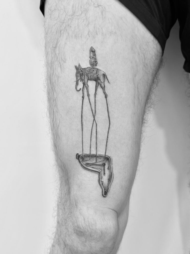 Tatuaje en línea fina de inspiración en Dalí en el muslo.