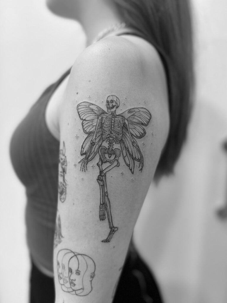 Tatuaje en brazo de esqueleto con alas