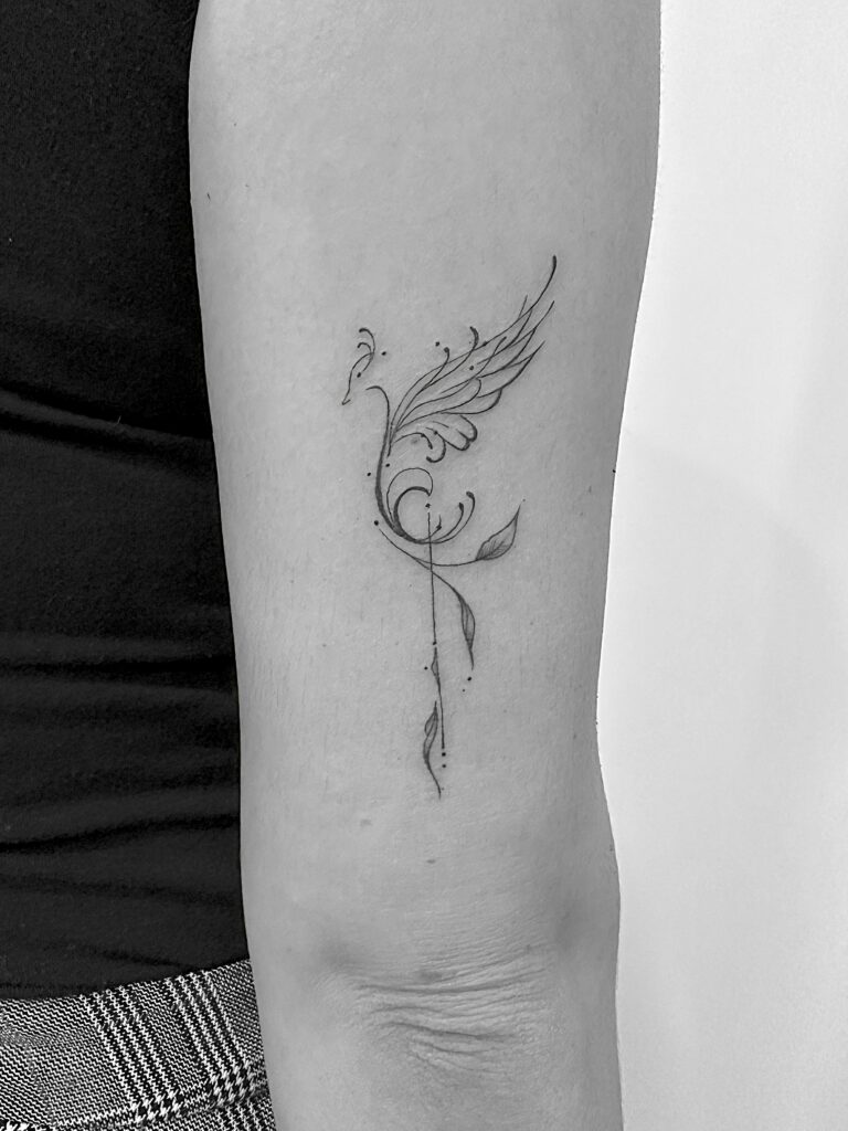 Tatuaje de línea fina de fénix minimalista en el brazo