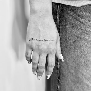 Tatuaje línea fina de palabra en la mano