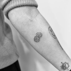 Tatuaje línea fina de mini pastas de té en antebrazo