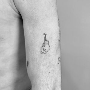 Tatuaje línea fina de guantes de boxeo en el brazo