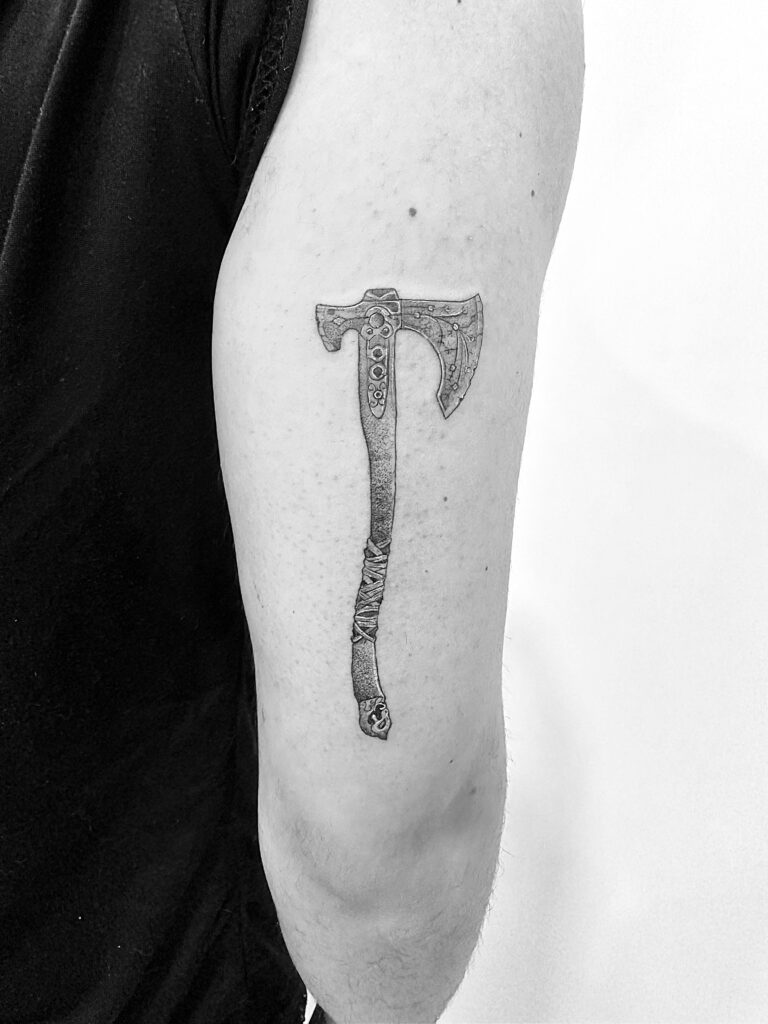 Tatuaje de línea fina de hacha "vikinga" decorada