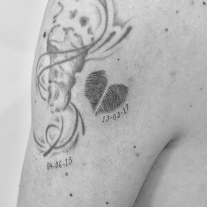 Tatuaje de huellas digitales en el hombro en forma de corazón con fecha de nacimiento