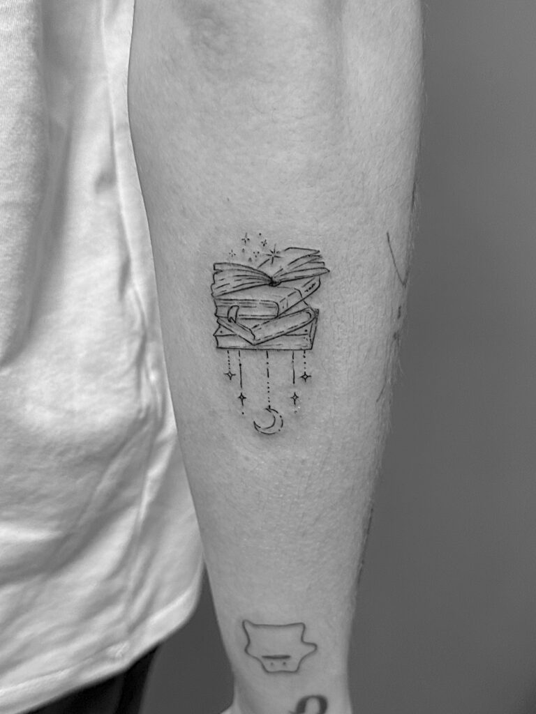 Tatuaje de línea fina de libros en el antebrazo