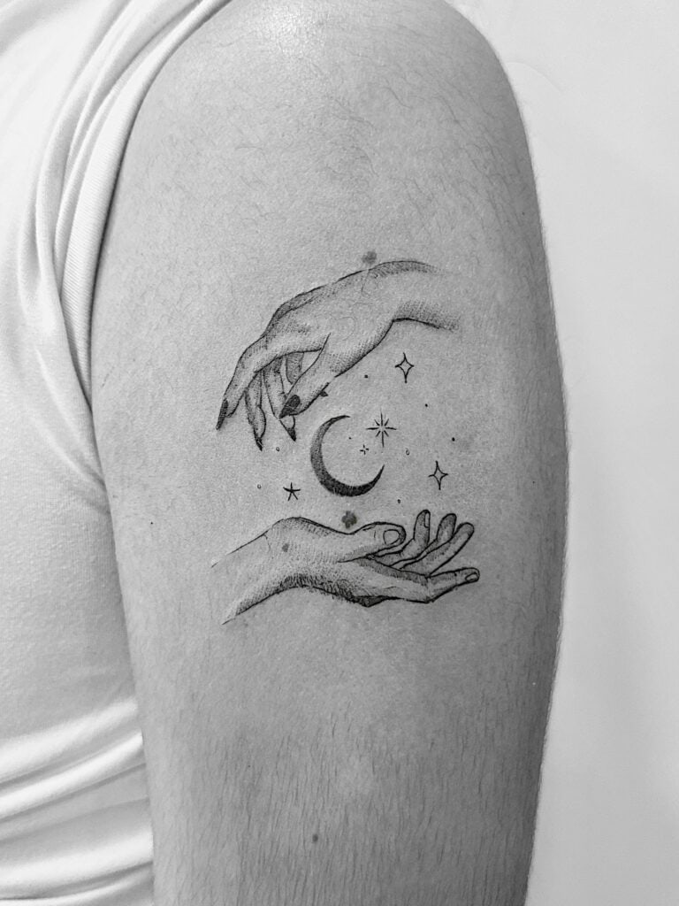 Tatuaje de línea fina de manos rodeando una Luna en el brazo