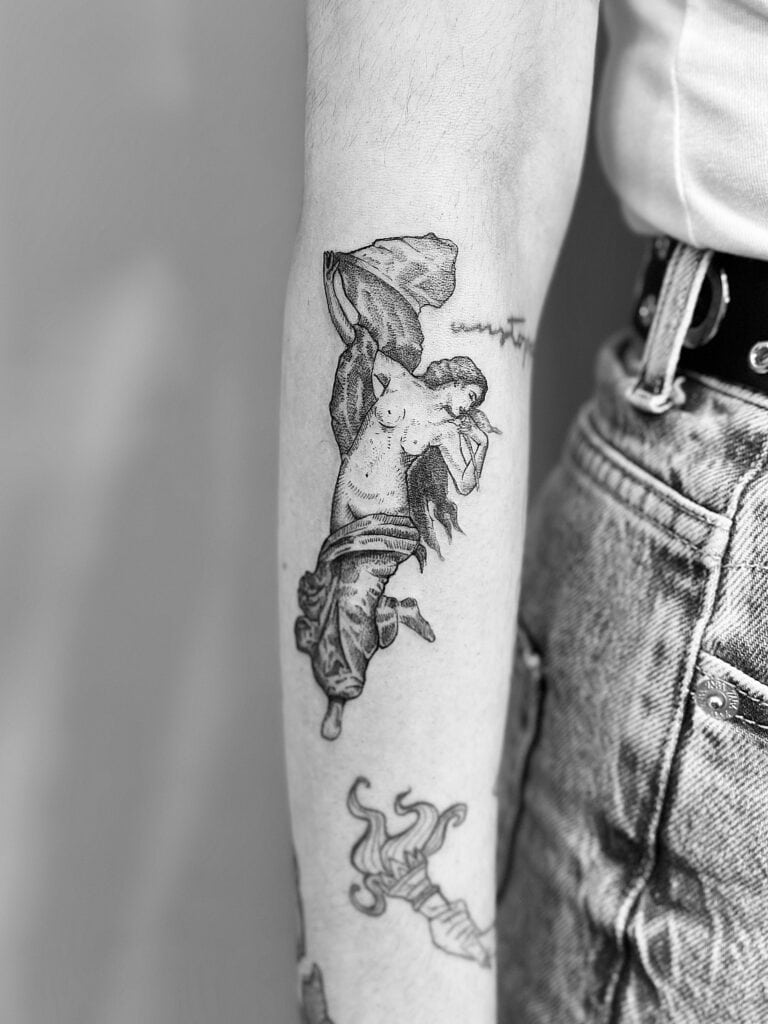 Tatuaje de mujer de inspiración clásica en el brazo