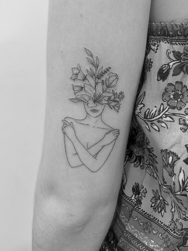 Tatuaje de línea fina de silueta de mujer con flores en la cabeza en el brazo