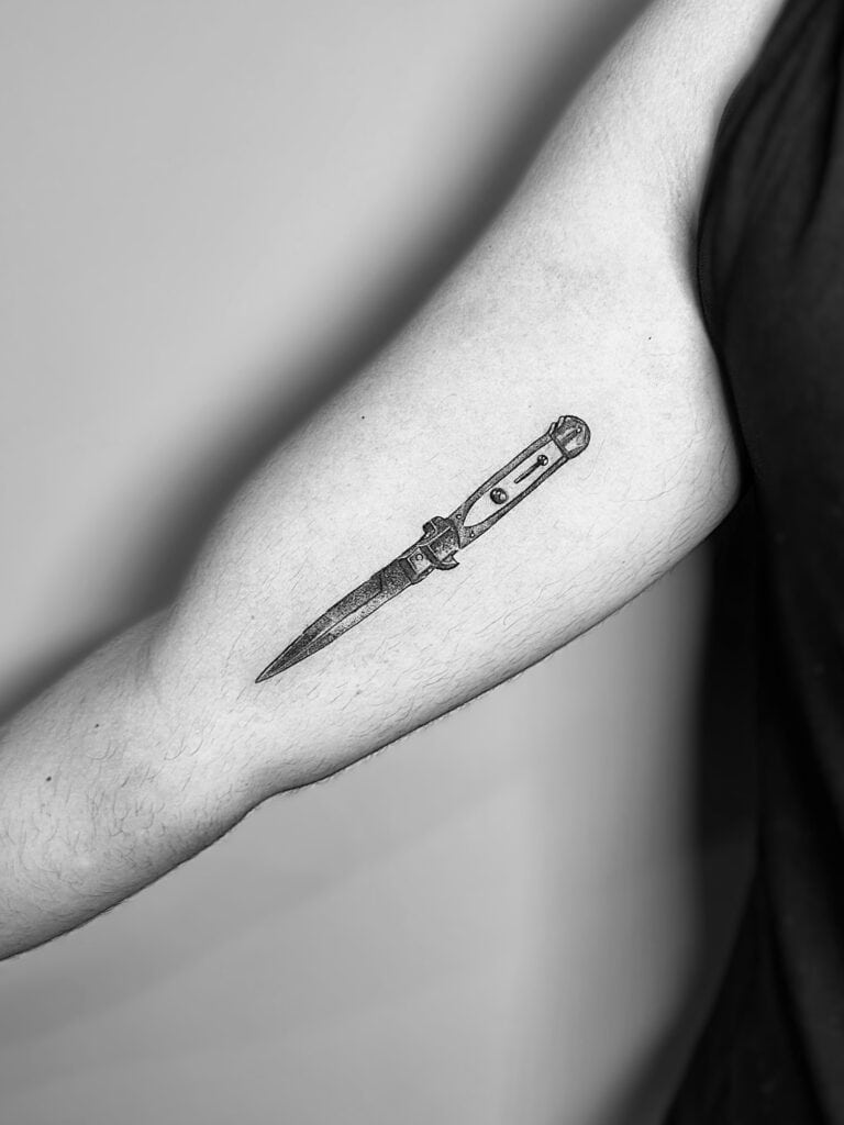 Tatuaje de línea fina de navaja en el brazo