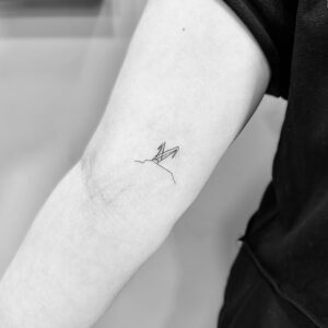 Mini pajarita de papel en el brazo