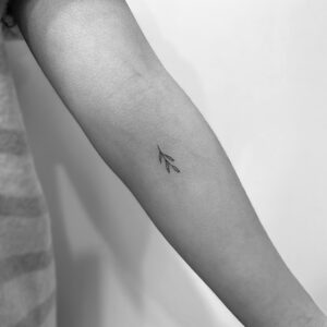 Tatuaje línea fina de ramita en el antebrazo