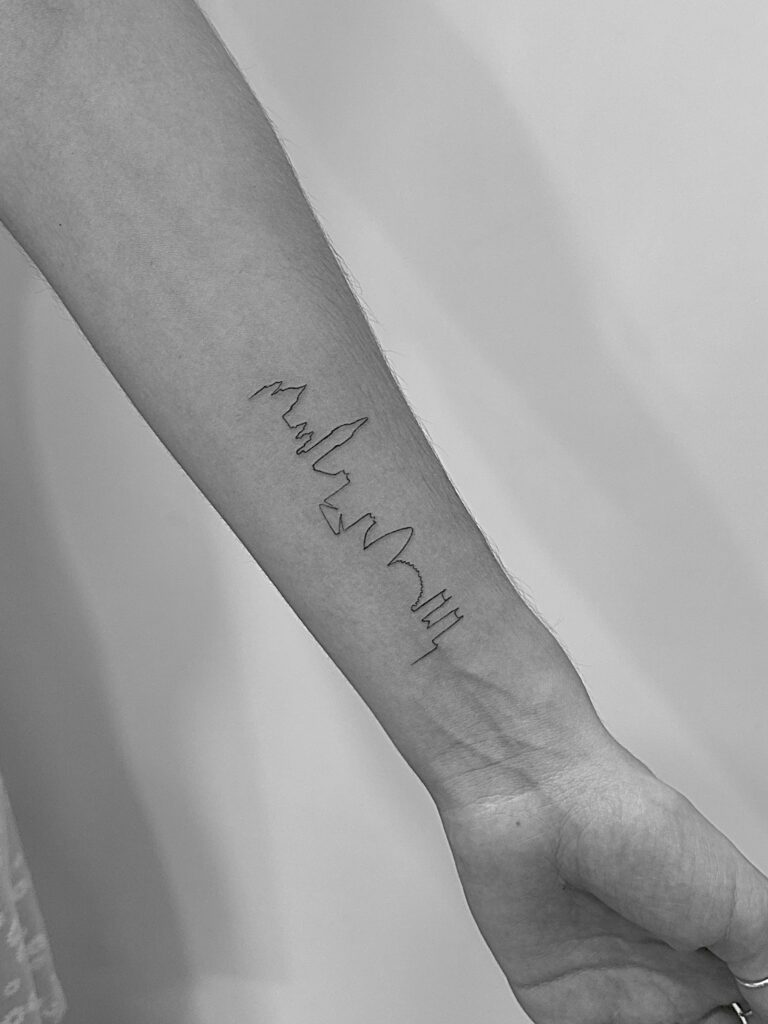 Tatuaje de línea fina de skyline en la muñeca