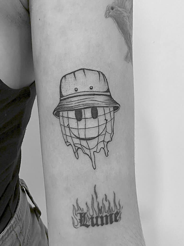 Tatuaje de smile con sombrero en el brazo