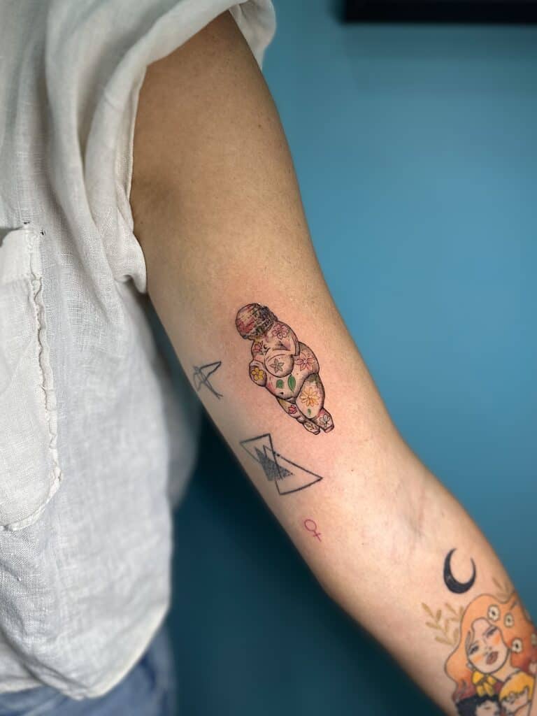 Tatuaje de Venus con tatuajes color en el brazo