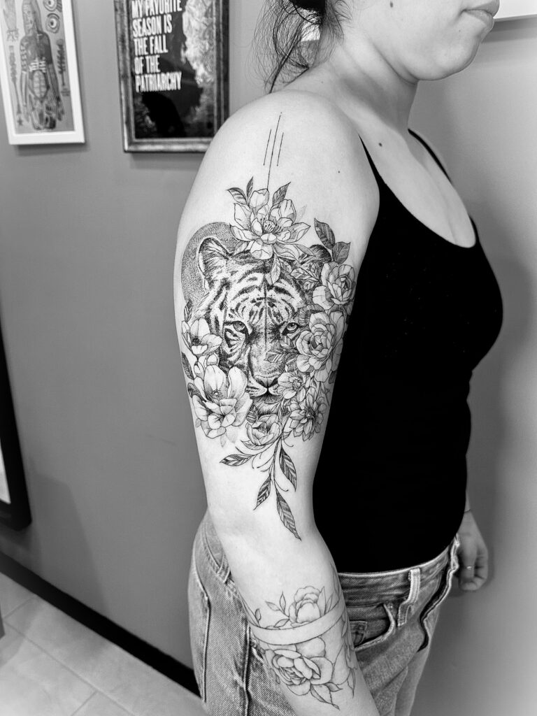 Tigre realista rodeado de flores en el brazo