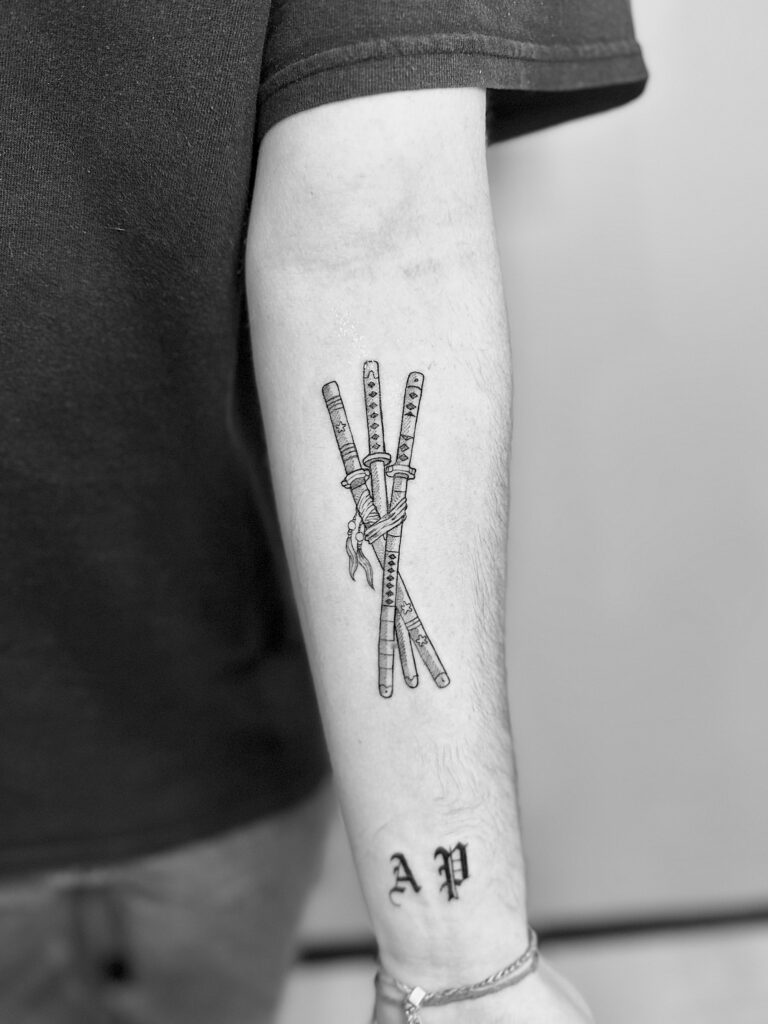Tatuaje de línea fina de tres katanas japonesas en el antebrazo