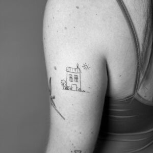 Tatuaje línea fina de casa infantil en brazo